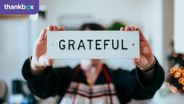 Person holding a sign saying 'grateful' and showing gratitude