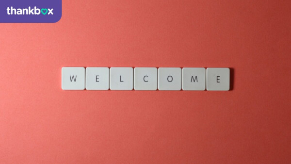 Close-up shot of keys on a red surface that spell "Welcome"