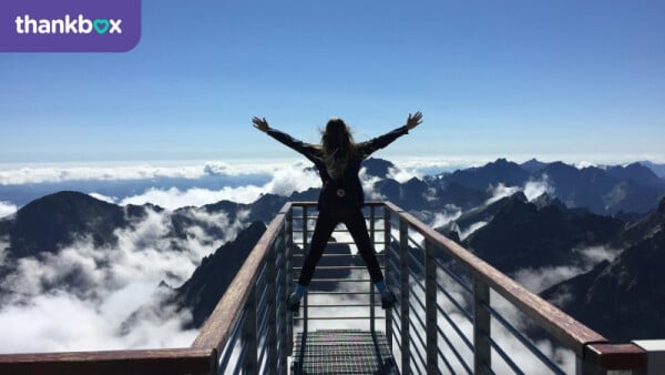 Woman Standing on Handrails With Arms Wide Open Facing the Mountains and Clouds