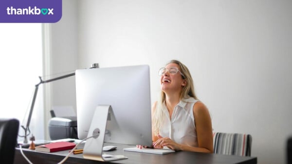 Woman in White Tank Top Using Macbook Air on Brown Wooden Table