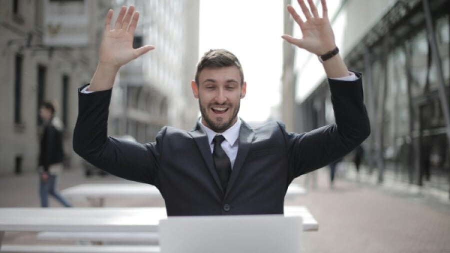 Man in black suit raising his hands in the air