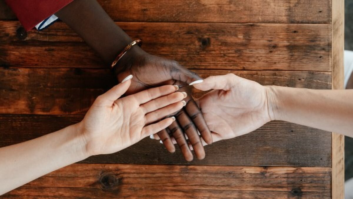 Diverse women stacking hands on wooden table