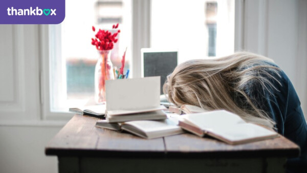 Tired woman rests her head on a pile of books