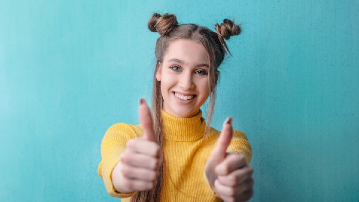 Woman in yellow turtleneck giving thumbs up