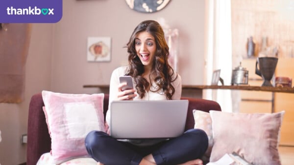 Woman sitting on a couch while using her laptop and smartphone