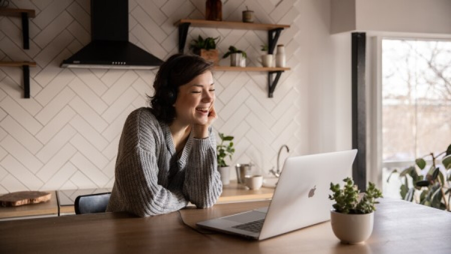 Smiling woman talking via laptop in kitchen