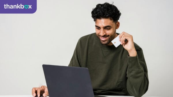 Man Holding A Credit Card and Using a Laptop